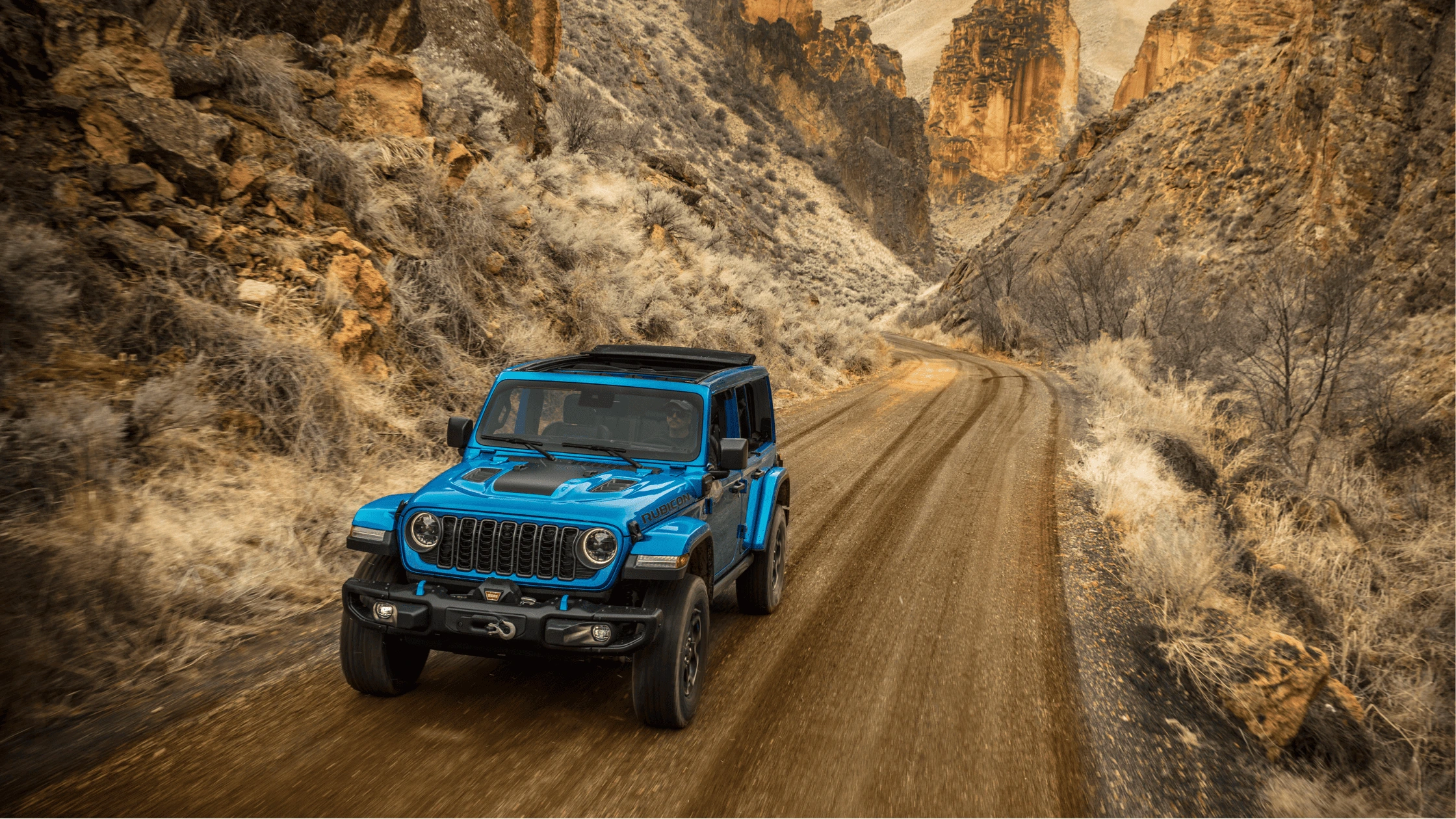 2025 Jeep Wrangler 4xe in bright blue navigating off-road desert trail near Fort Myers