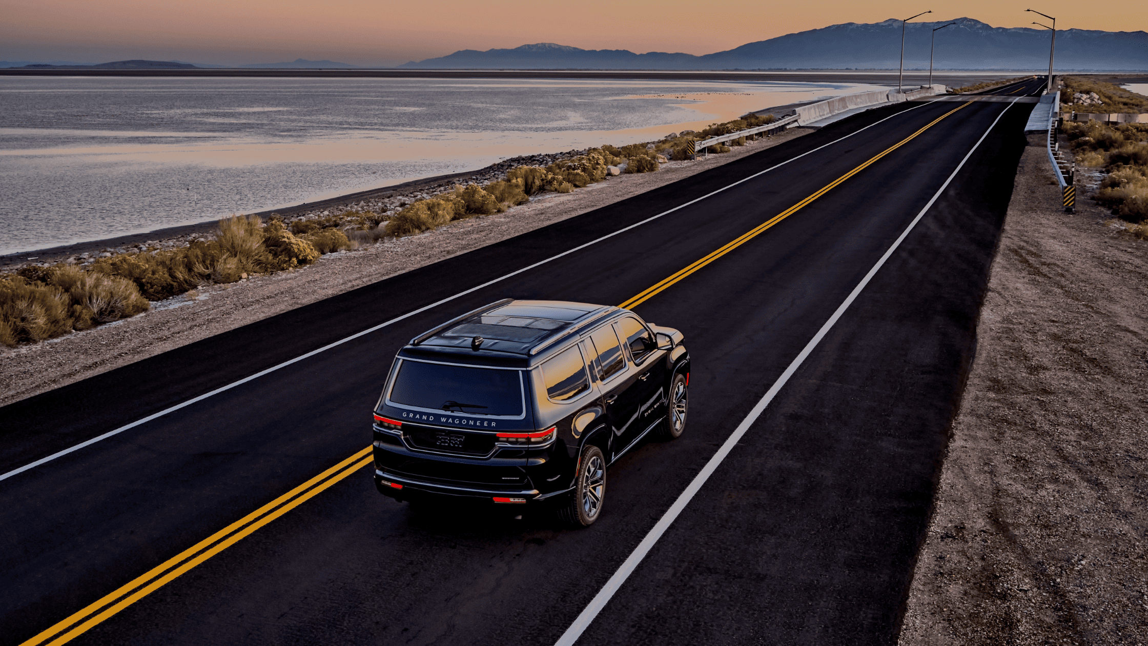 The 2024 Jeep® Grand Wagoneer driving along a scenic coastal road near Fort Myers, showcasing its luxury, versatility, and capability for both beach days and city drives.