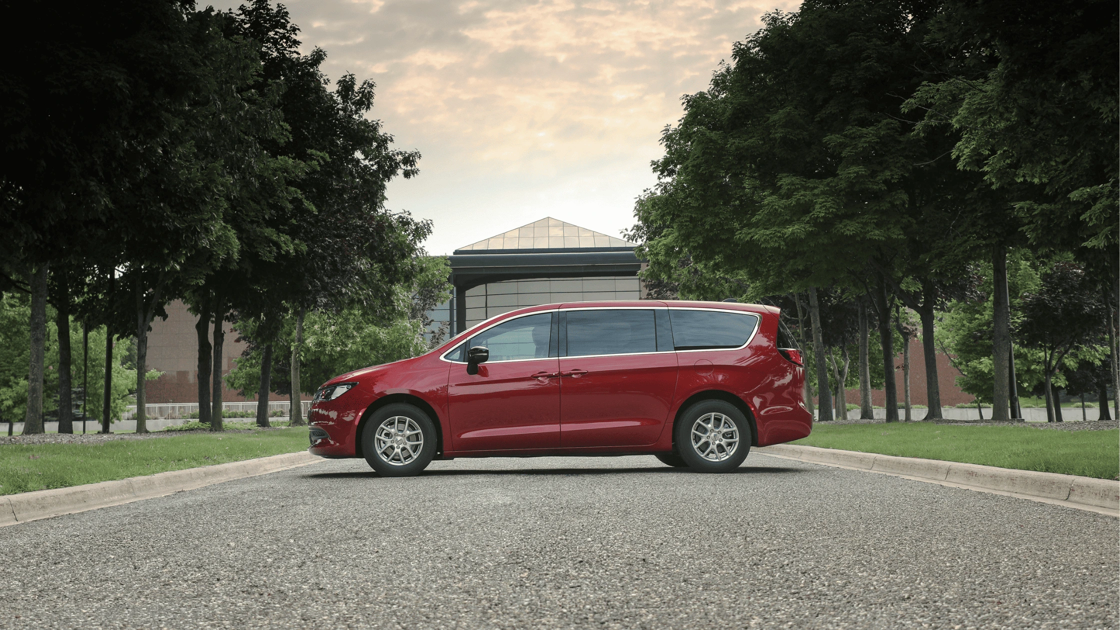A side profile of the red 2025 Chrysler Voyager parked on a scenic suburban street in Fort Myers, FL.