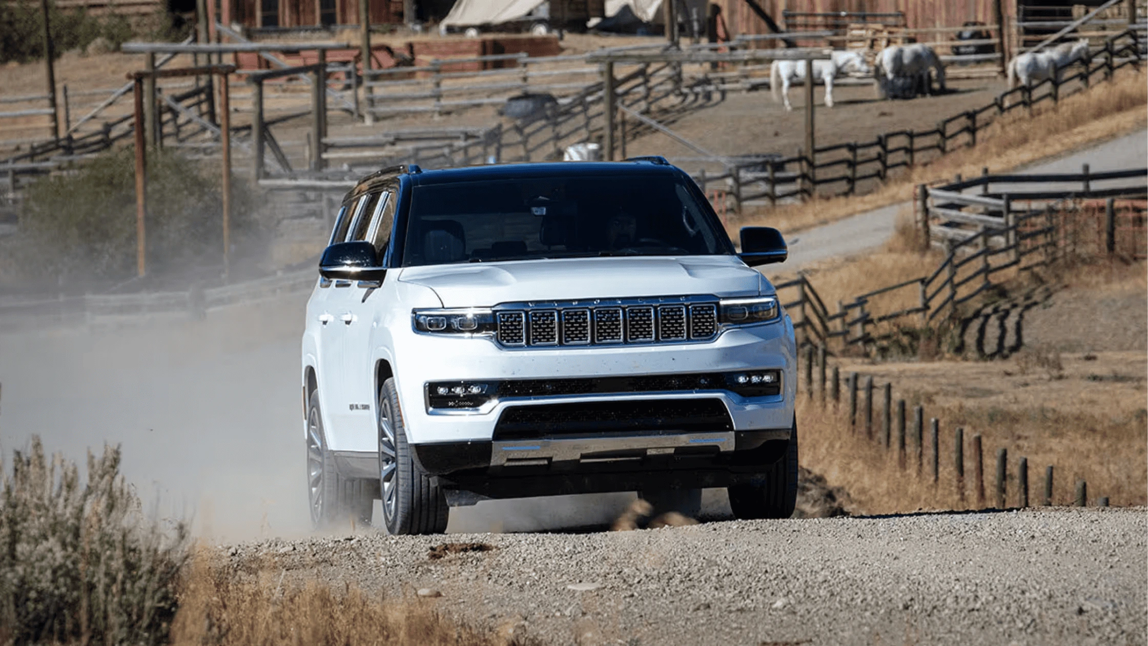 The 2025 Jeep Grand Wagoneer driving on a rugged dirt road, showcasing its off-road capability, luxury SUV design, and iconic seven-slot grille.