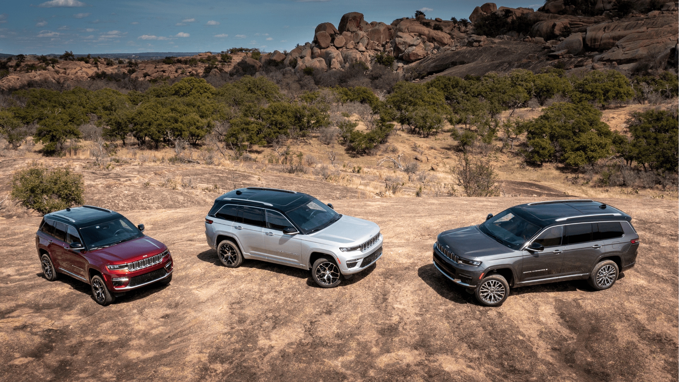 Silver 2025 Jeep Grand Cherokee L by a bridge with water and skyline in background