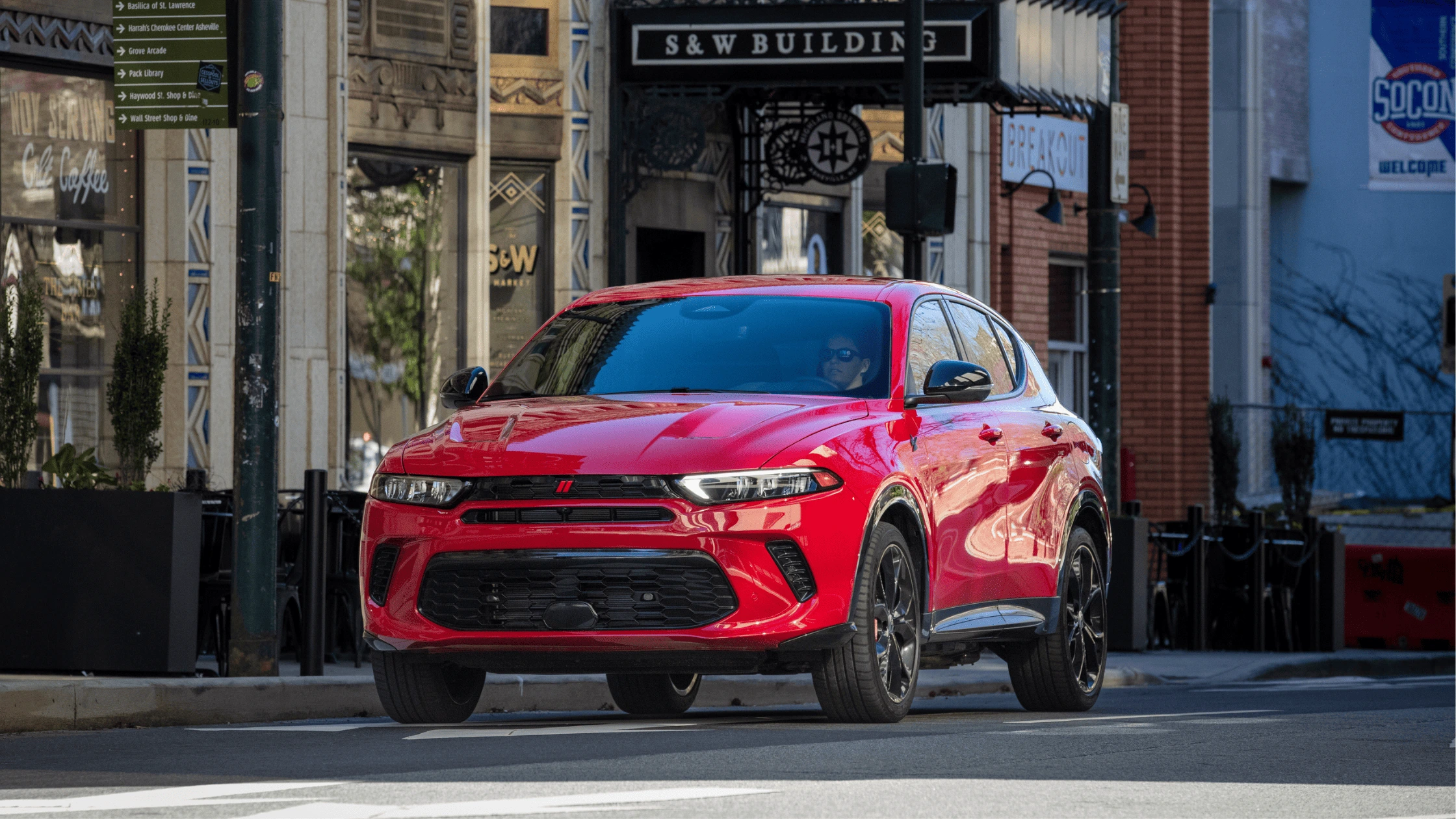 A bold red 2025 Dodge Hornet driving through vibrant city streets in Fort Myers, FL.