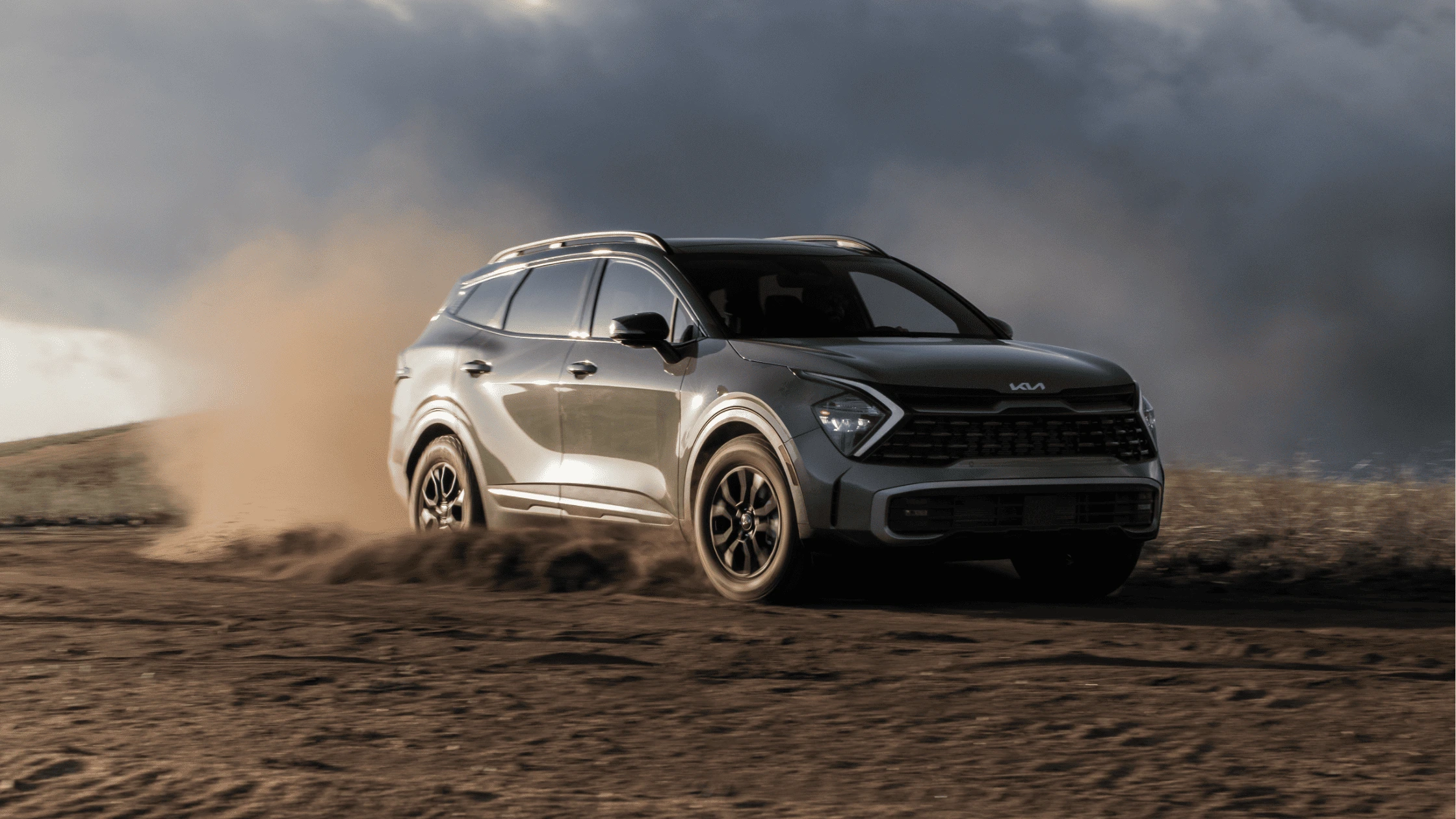 The 2025 Kia Sportage kicking up dust as it drives through an open field, emphasizing its off-road capabilities in Fort Myers.