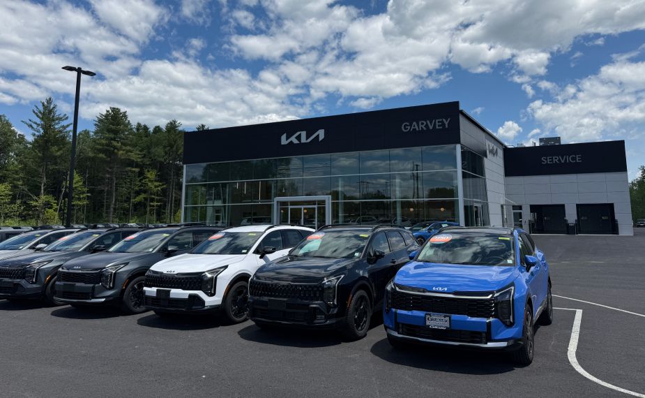 Kia vehicles of different trims in front of new dealership building