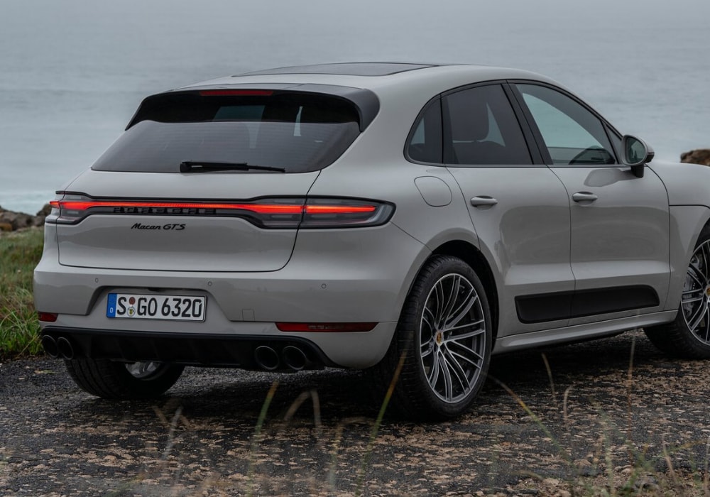 Rear passenger side exterior angle of a white 2020 Porsche Macan with the brake lights shining