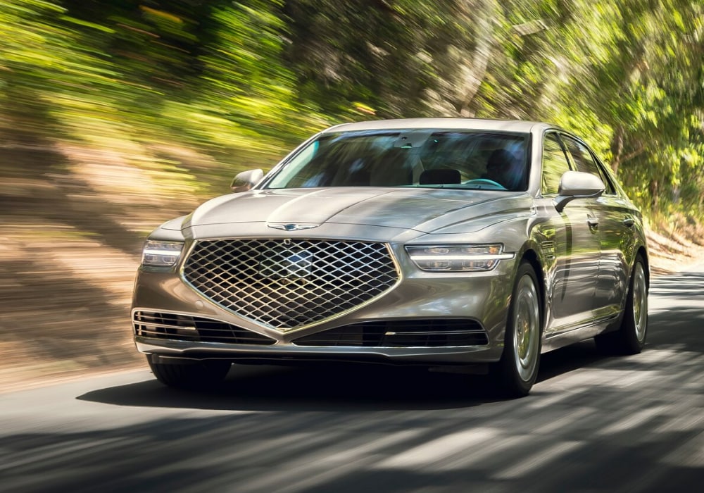 2020 Genesis G90 Exterior Design.png 2020 Genesis G90 sedan in gold coast silver color driving down an open road at high speeds