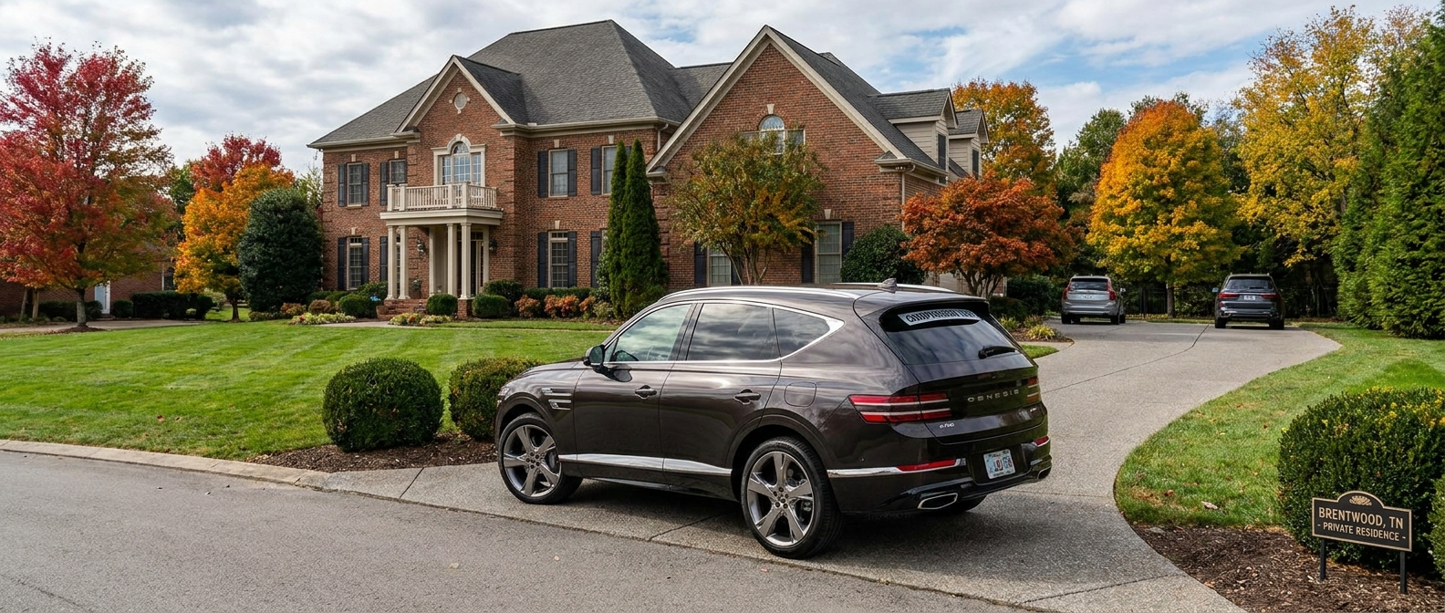 2026 Genesis GV80 parked on a Brentwood Tennessee suburban driveway in autumn, a family-sized three-row luxury SUV compared with the Volvo XC90