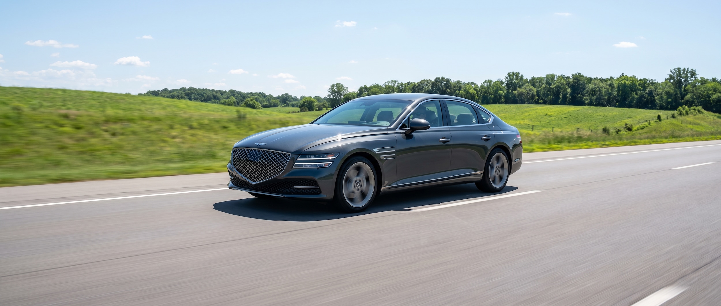 A 2026 Genesis G80 in a refined dark or silver exterior color traveling west on a wide, flat Tennessee interstate under an open midday sky, slight motion blur on the road surface to suggest highway speed, no other vehicles in frame, clean and composed compositionA 2026 Genesis G80 in a refined dark or silver exterior color traveling west on a wide, flat Tennessee interstate under an open midday sky, slight motion blur on the road surface to suggest highway speed, no other vehicles in frame, clean and composed composition