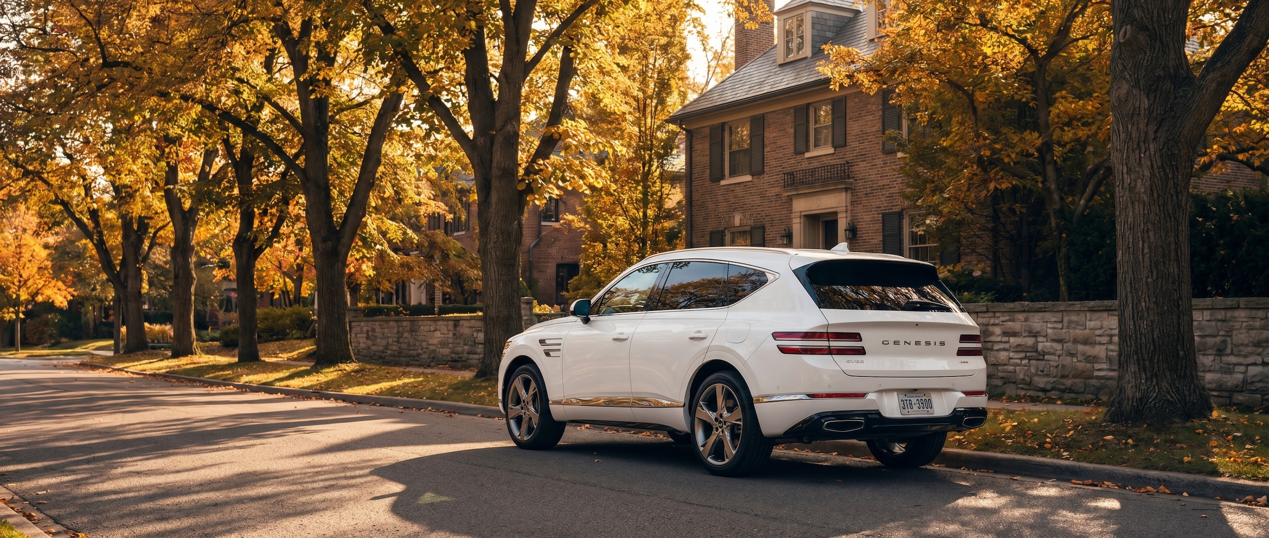 A white Genesis GV80 parked on a tree-lined suburban street in autumn, with warm golden light filtering through the leaves, evoking the refined residential feel of the Franklin and Brentwood area south of Nashville.