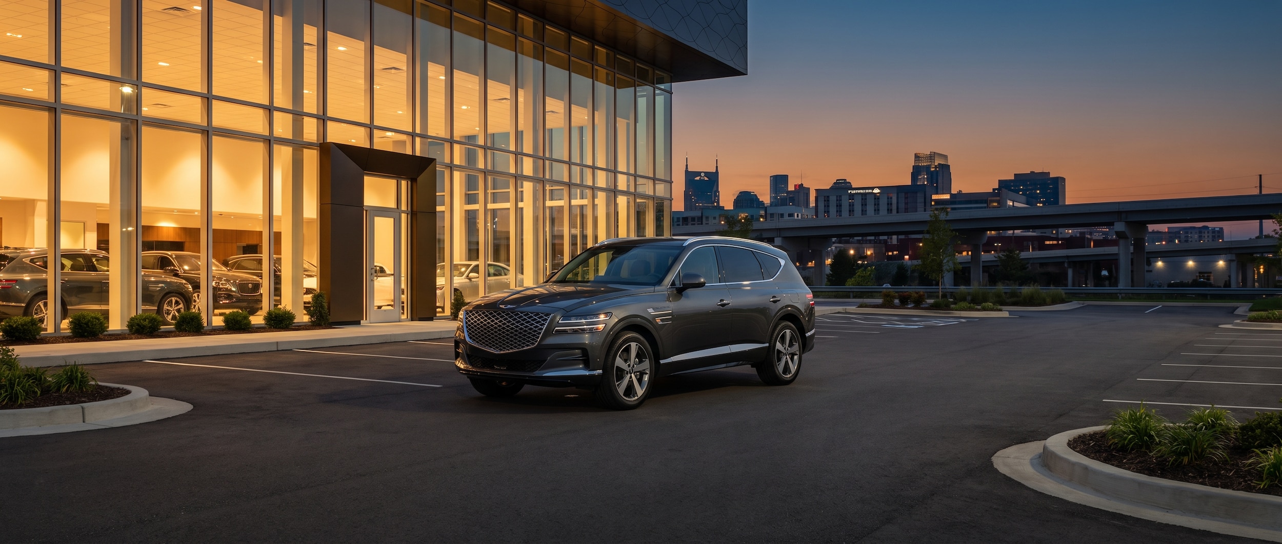A 2025 or 2026 Genesis GV80 parked at a modern dealership entrance at dusk, with warm interior showroom lighting visible through glass. The setting should feel urban-suburban, with a clean parking lot and a low Nashville skyline or highway overpass subtly visible in the background. No price tags or banners.