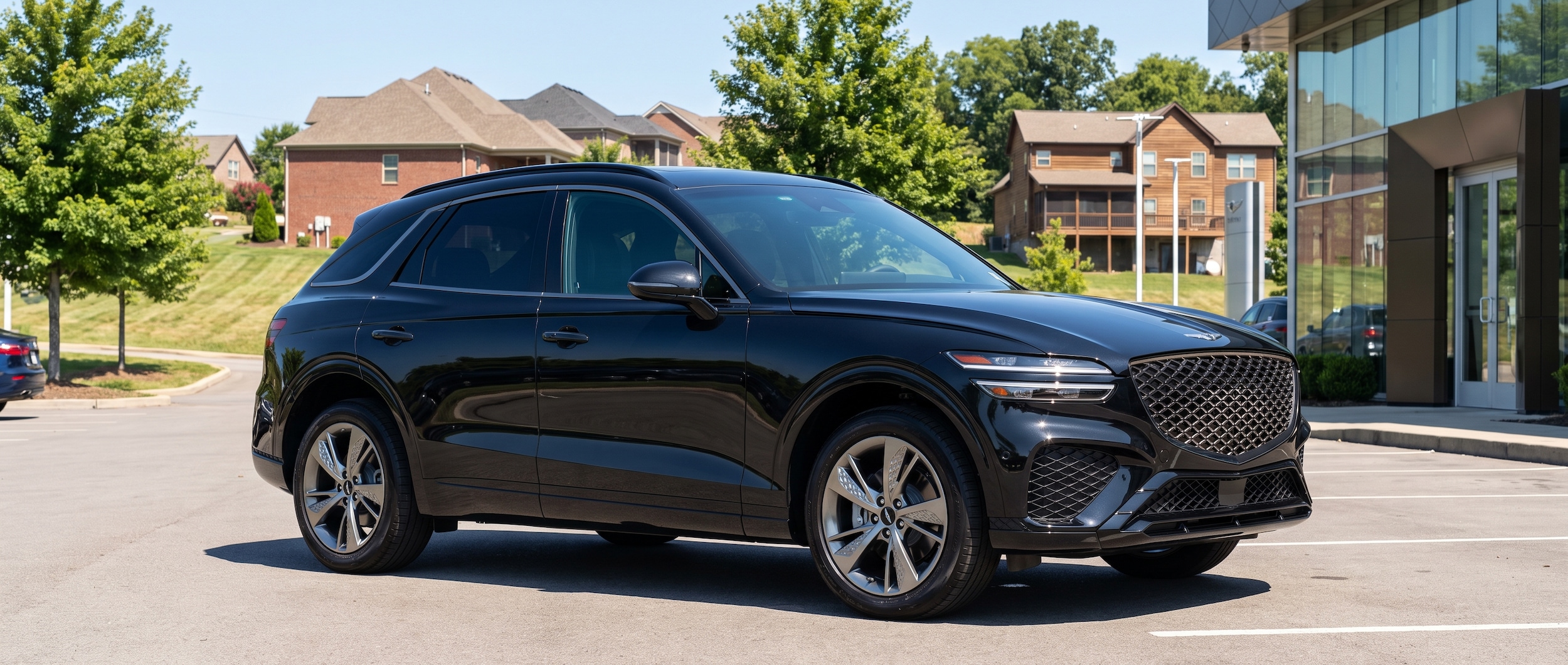 A 2026 Genesis GV70 in Vik Black parked in a clean suburban Nashville dealership lot on a bright summer afternoon, South Nashville architecture visible in the background, blue sky, lush green trees