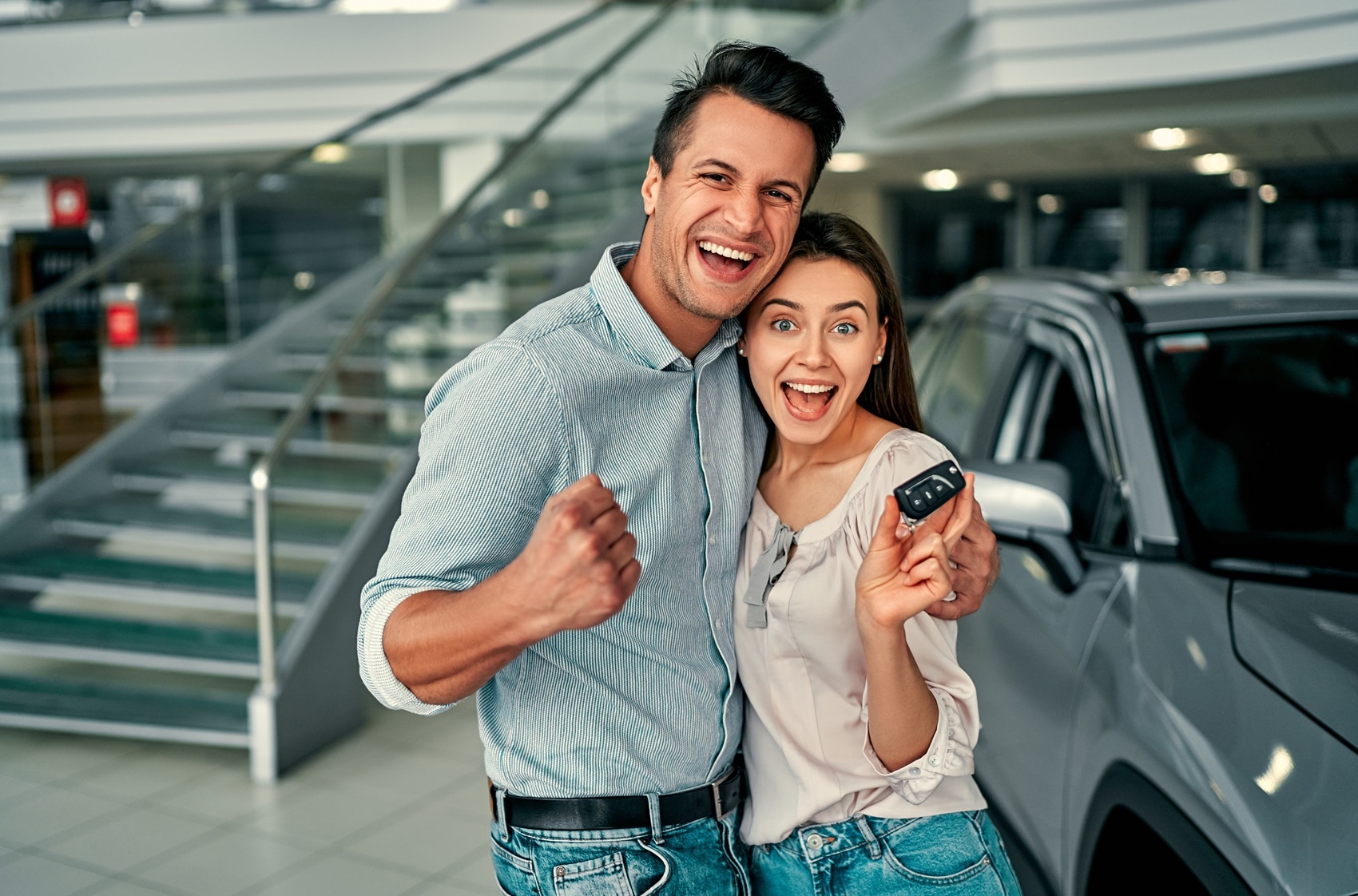 Couple smiling at camera and holding up keys to their new Volkswagen vehicle from Volkswagen Dealer near Caldwell NJ