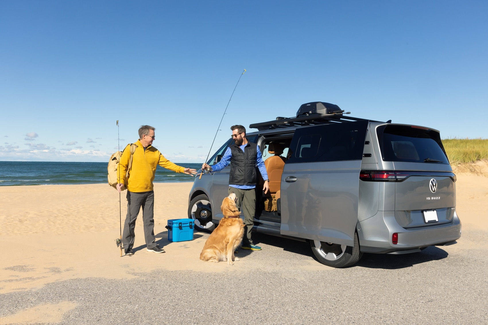 Two men and a dog next to Volkswagen ID. Buzz parked by the water grabbing fishing gear out of vehicle from Volkswagen Dealer near Caldwell NJ