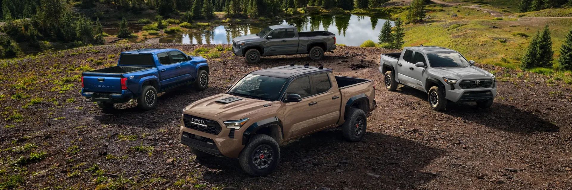 4 Toyota Tacoma Truck Models parked by a lake