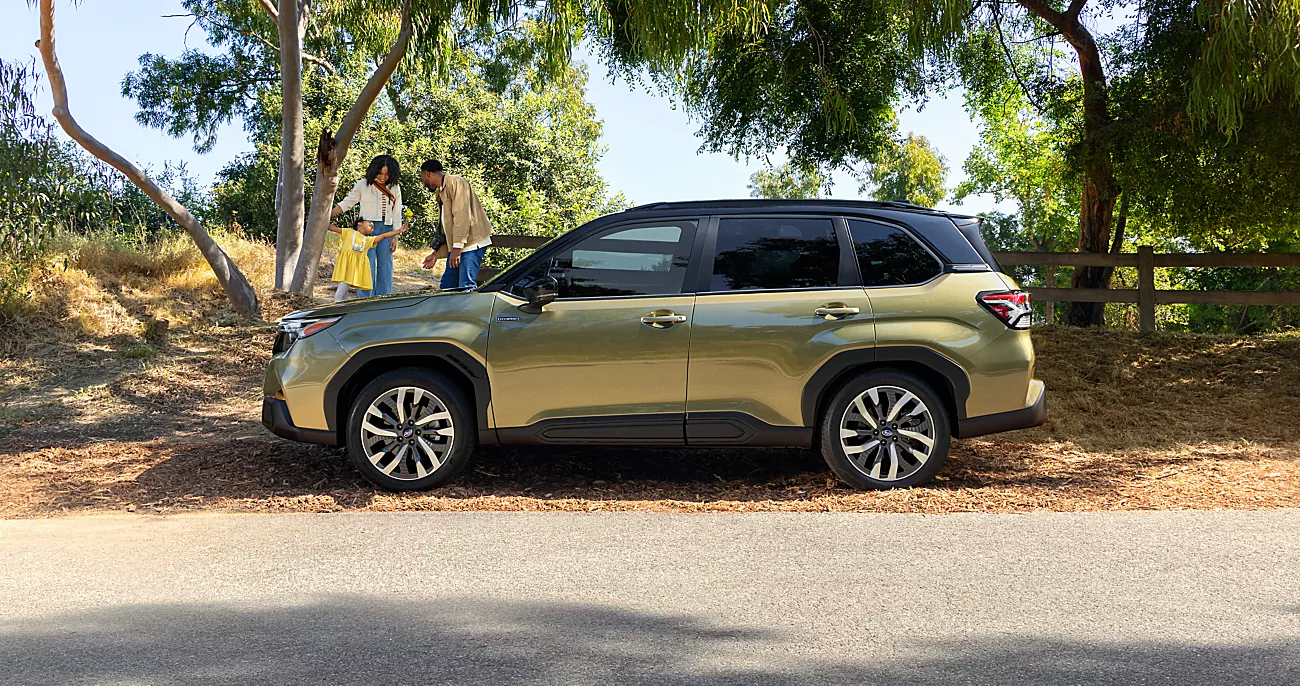 2025 Gold Metallic Subaru Forester on the side of the road with a family.