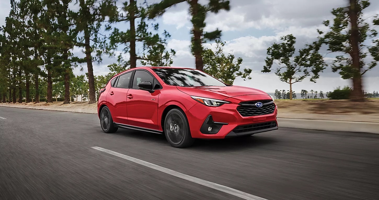 2025%204Runner%20Price%20and%20Trim.png Red 2025 Subaru Impreza driving down a road lined with trees.