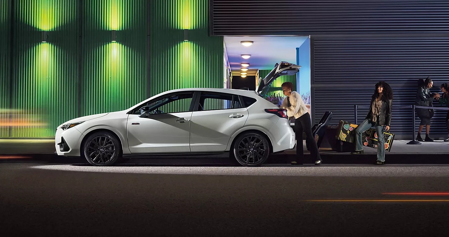 Two musicians loading their musical equipment into the trunk of the 2025 Subaru Impreza.