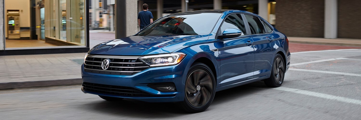 Blue VW Jetta turning a downtown corner