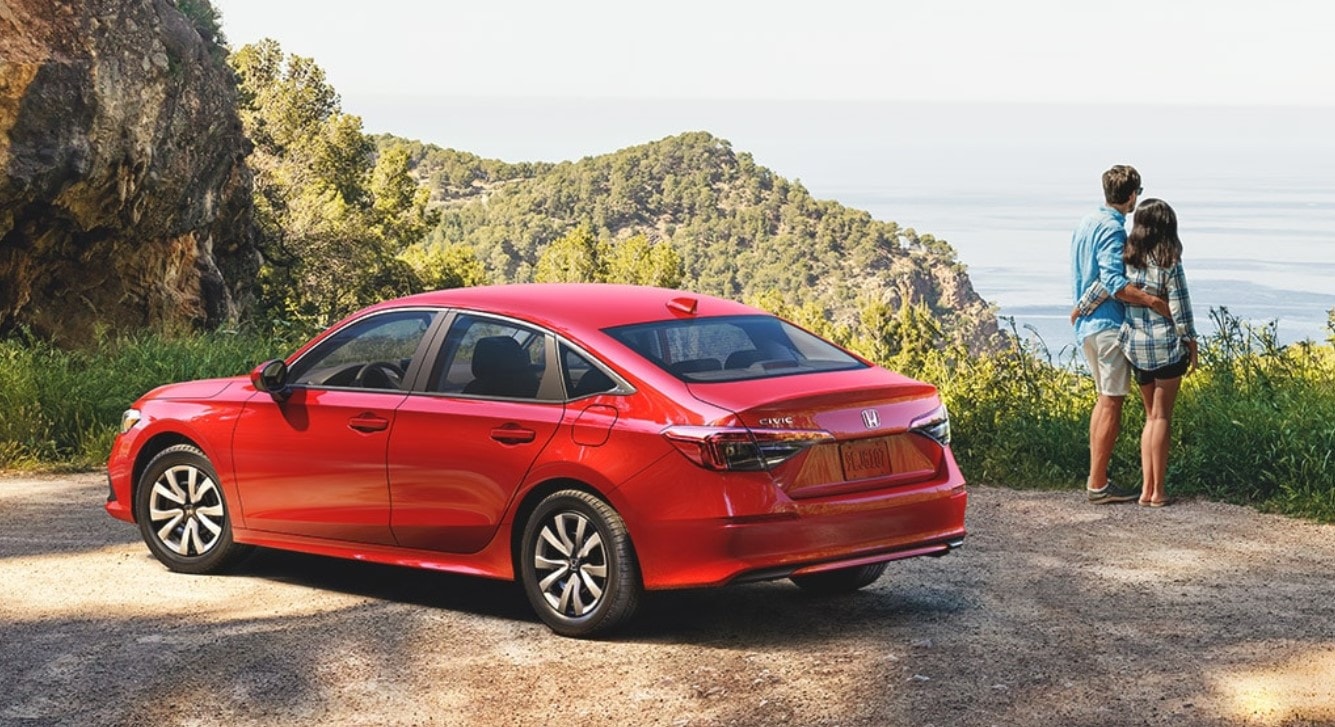 Honda Civic parked at scenic viewpoint with couple looking at ocean