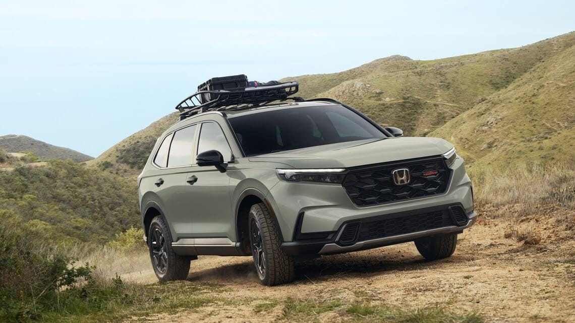 AHonda CR-V driving off-road in a hilly area.