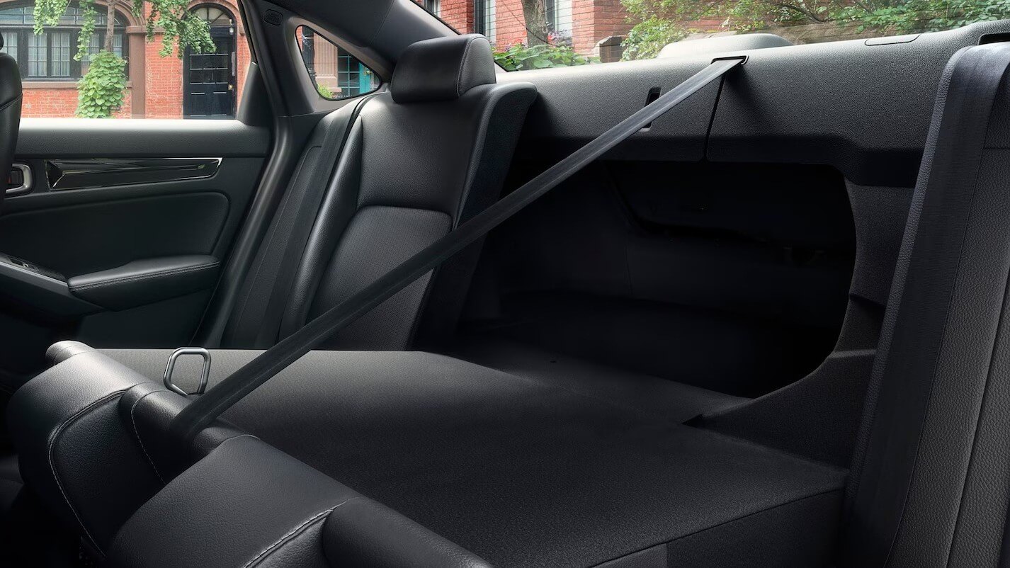  The back seat of a Honda Civic with a seatbelt stretched out.