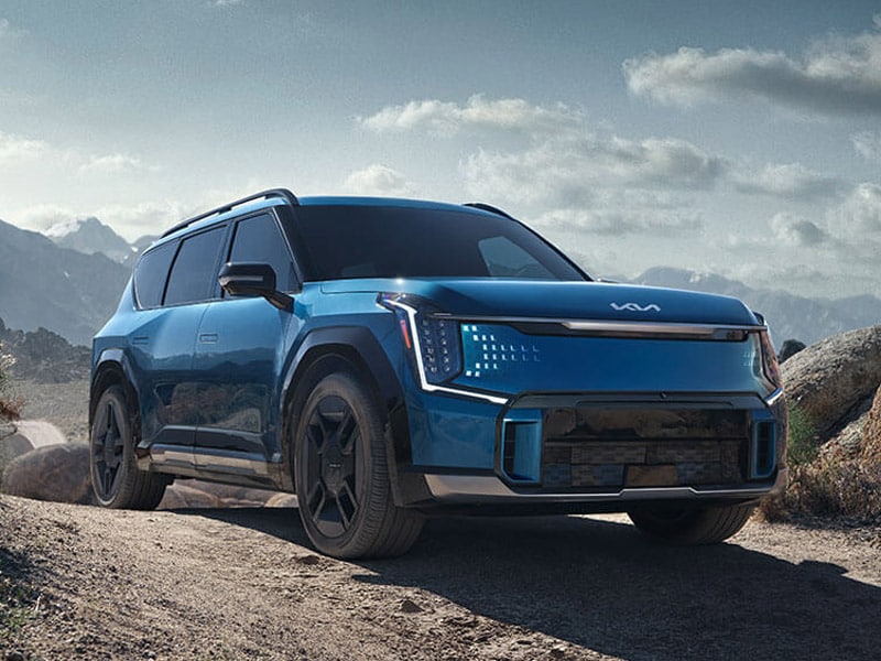 Blue Kia EV9 electric SUV parked on a mountain trail