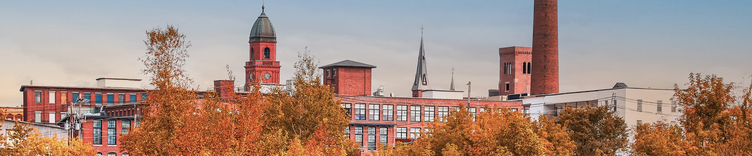 Scenic view of the Lewiston-Auburn, Maine area with historic mill buildings and fall foliage.