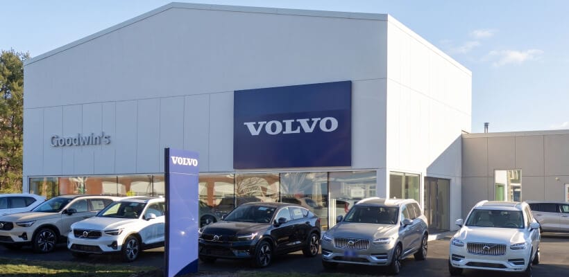 Front exterior view of Goodwin's Volvo dealership building with a row of Volvo cars parked in front.