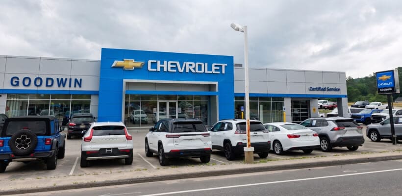 Front exterior view of Goodwin Chevrolet dealership with a row of cars parked in front.