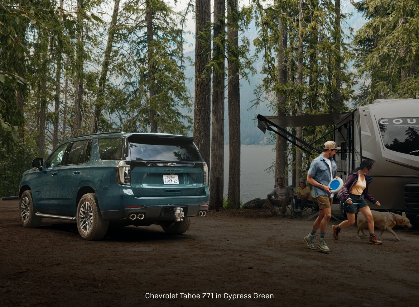 Chevrolet Tahoe hooks to a camper trailer at a lakeside campground.