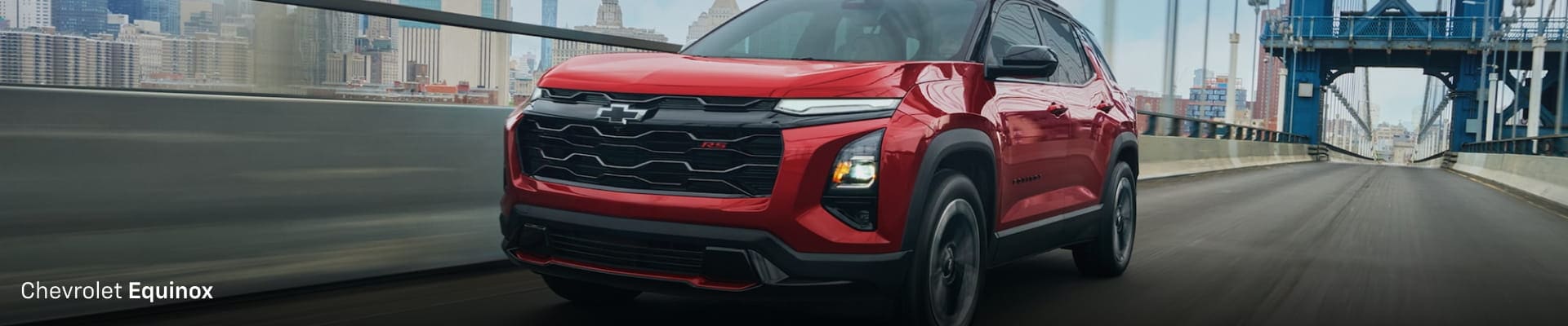 Red Chevrolet Equinox driving on a city bridge with a blurred urban skyline in the background.