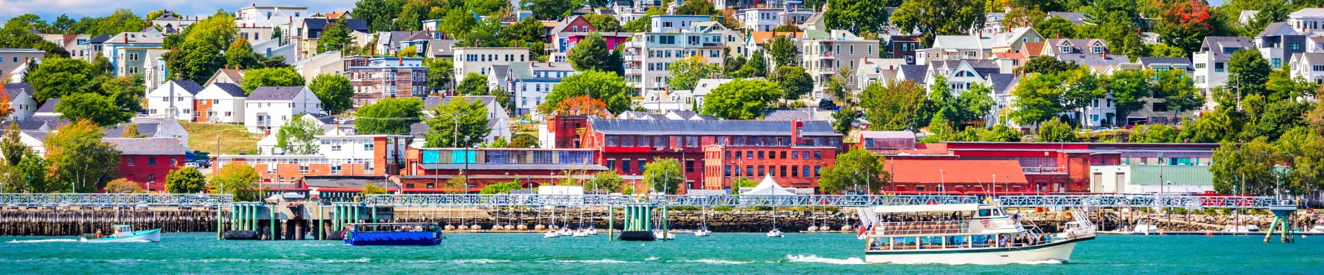 Waterfront view of Portland with boats, colorful buildings, and homes along the shoreline.