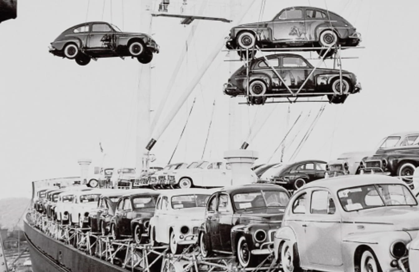 Historic black-and-white photo of vintage Volvo cars being loaded onto a cargo ship.