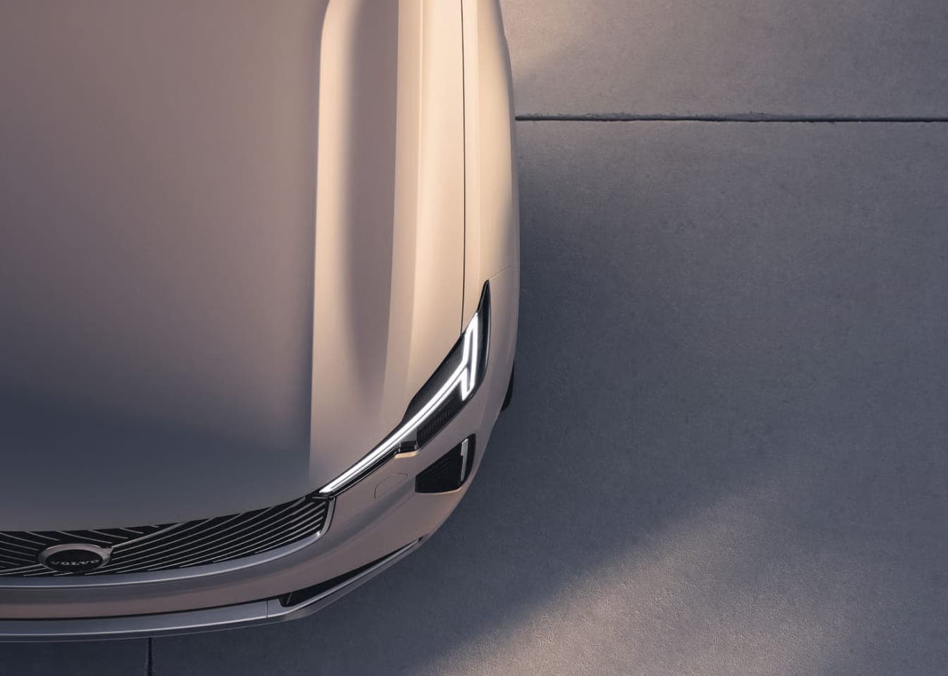 Close-up overhead view of a Volvo front end featuring the grille and illuminated headlight.