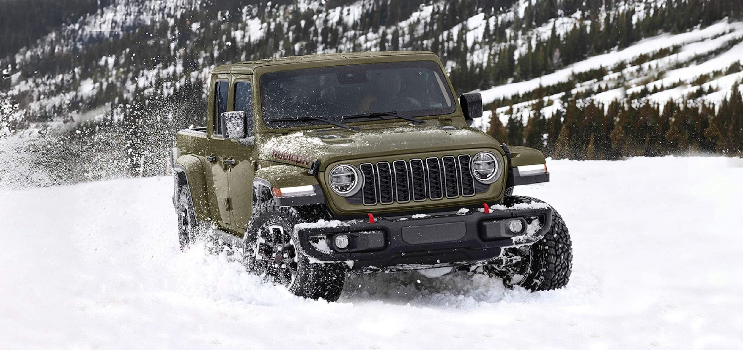 An army green Jeep Gladiator driving through the snow