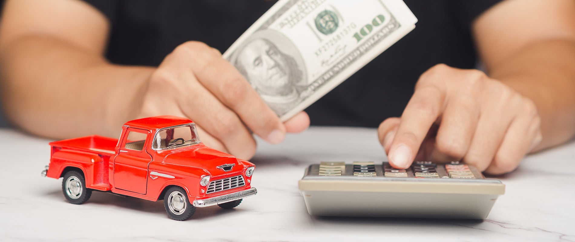 A man calculating the cost of an auto lease while holding cash.