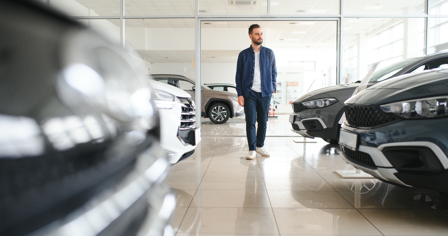 Young man browsing through car dealership.