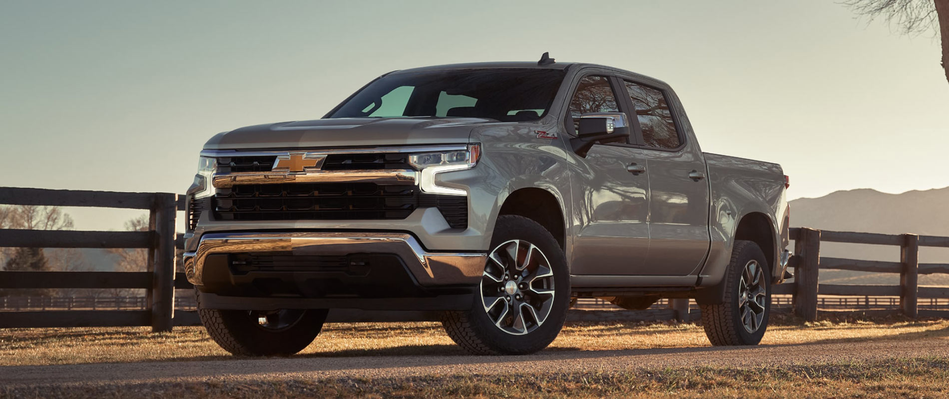 A gray Chevrolet Silverado 1500 parked by a fence on a farm.