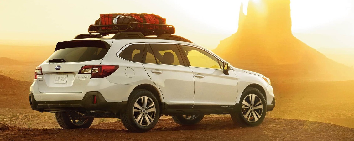 2018 Subaru Outback parked on a desert cliff overlooking a sunset