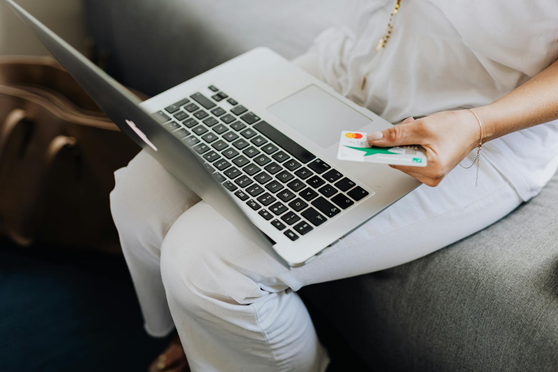 photo of a person using a laptop holding a credit card