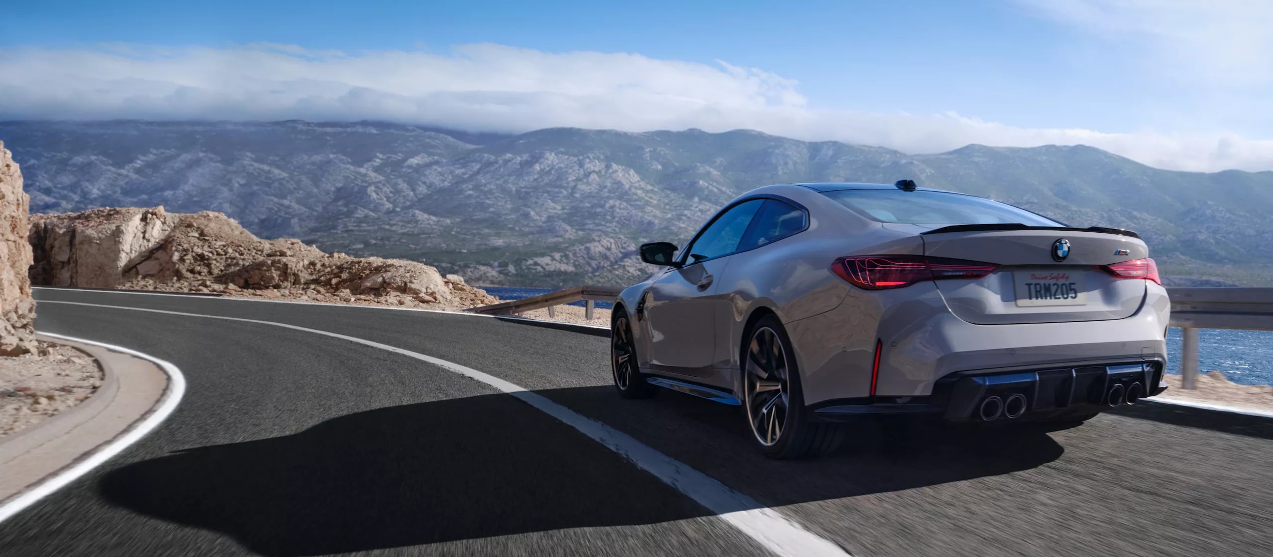 A gray bmw 4 series driving on the road.