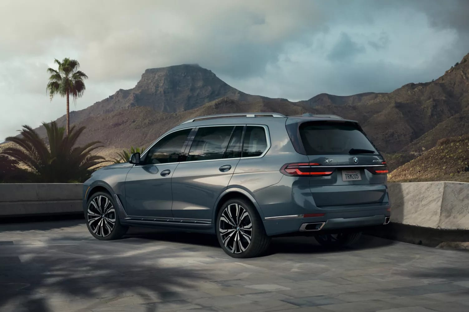 A bmw x7 sitting parked with mountains in the background.