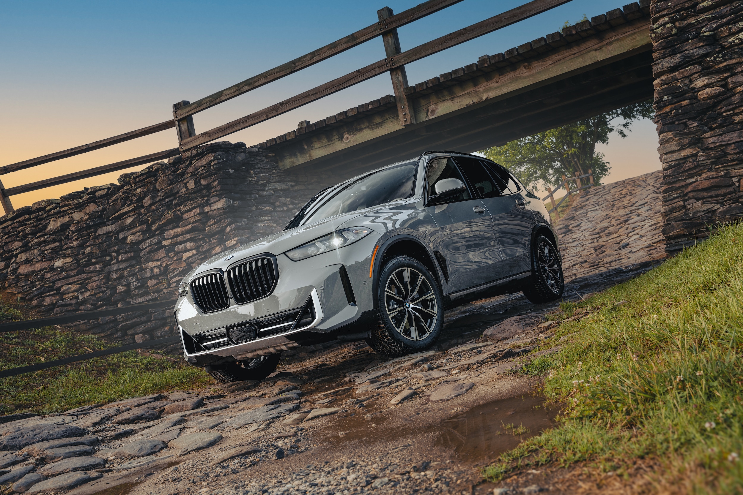 The 2026 BMW X5 driving under a bridge