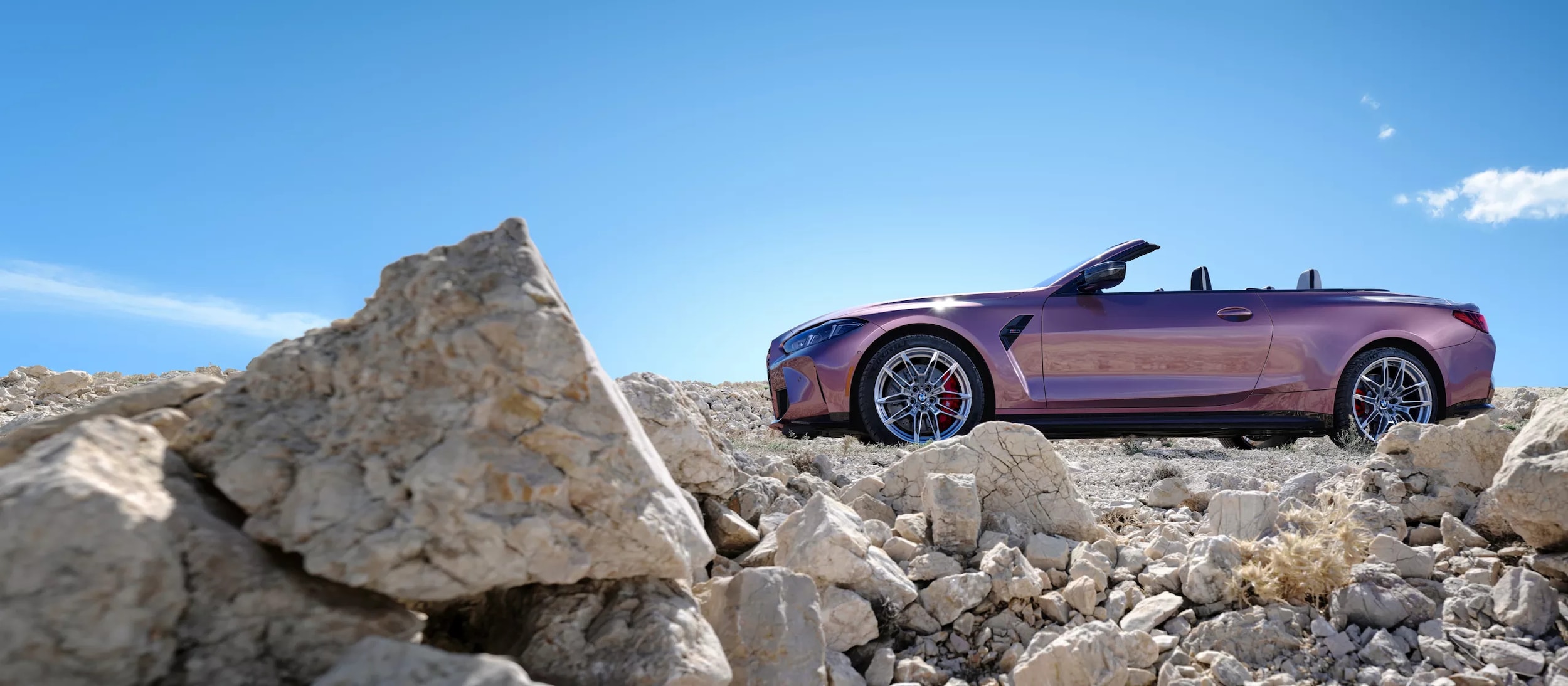A bmw m4 convertible sittting parked off-road.