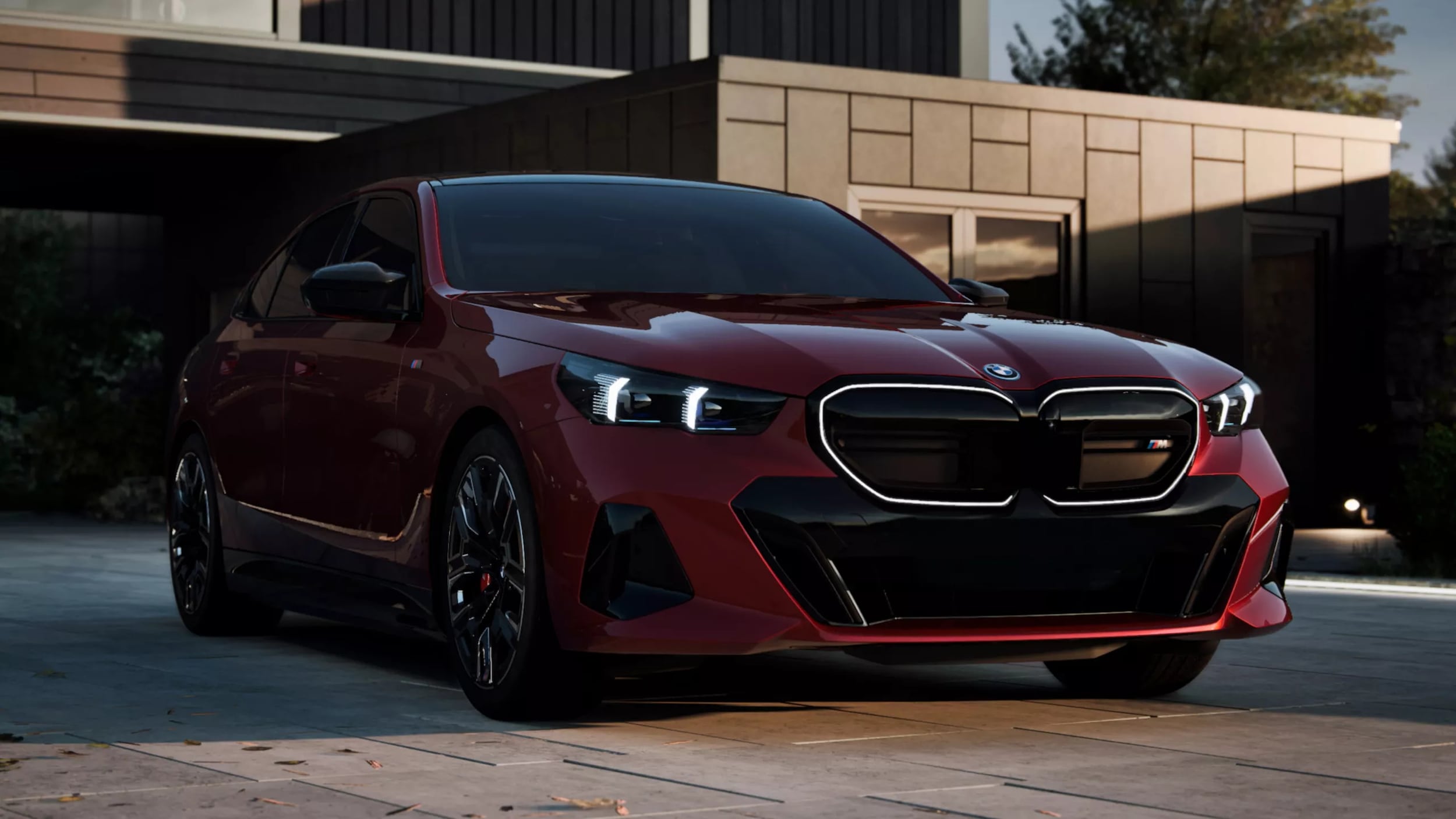 A red BMW i5 sitting parked in front of a house.