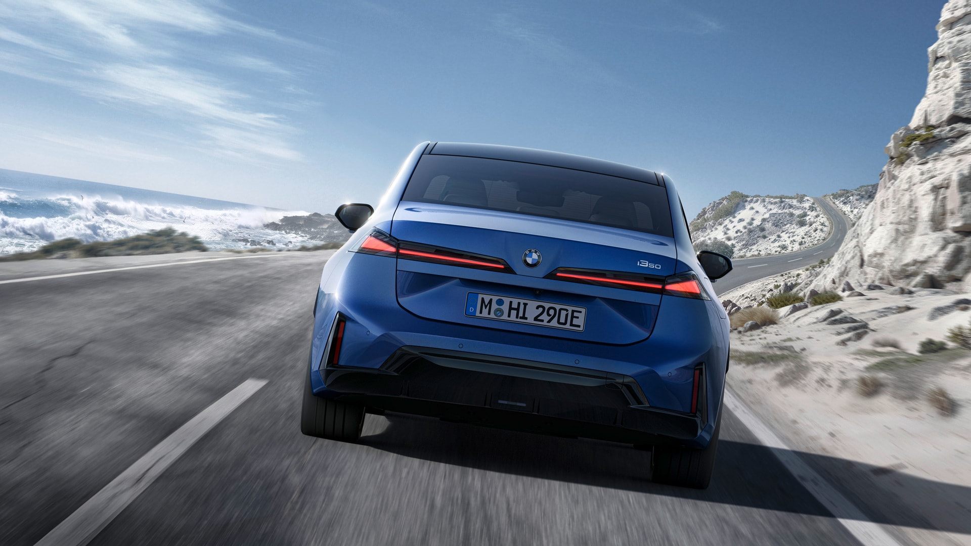 The 2027 BMW i3 driving on a road along the side of a mountain