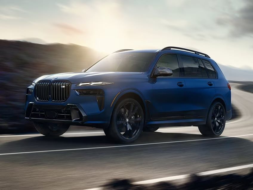 a blue 2027 bmw x7 m60i driving on a curved road