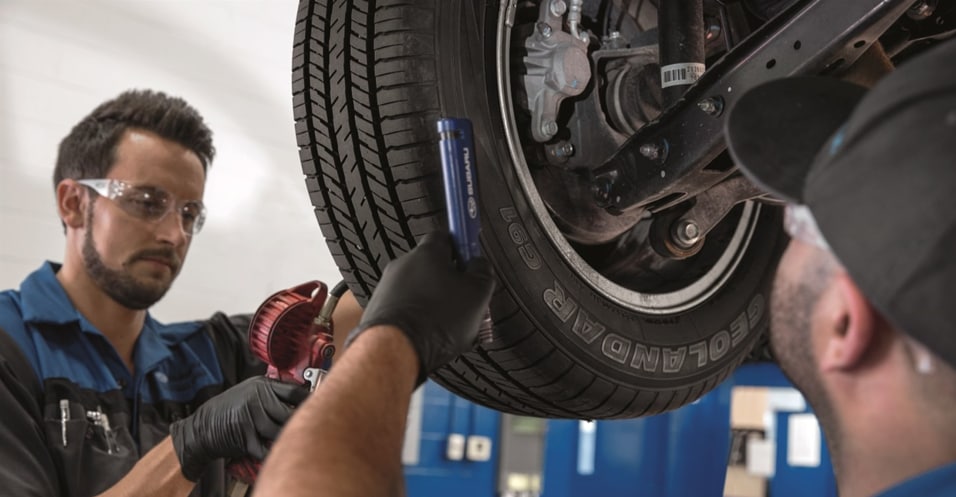 Technicians performing tire rotation and alignment service.png