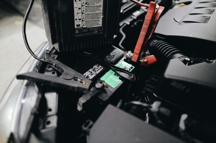 Vehicle battery with red and black jumper cable clamps attached