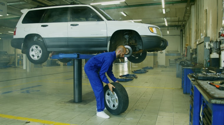 A%20Man%20in%20Blue%20Coveralls%20Holding%20a%20Tire.PNG